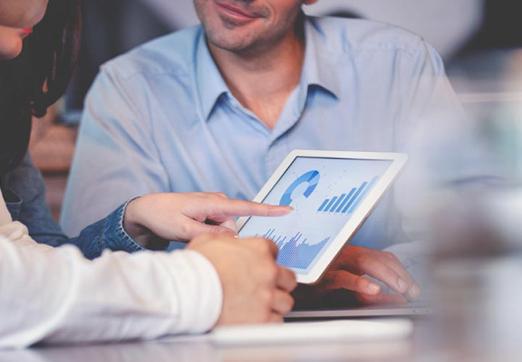 Financial advisor showing clients projected numbers on a tablet.