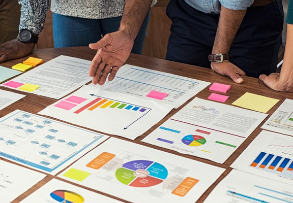 Closeup business man and businesswoman hands understanding pie and bar graphs during meeting.