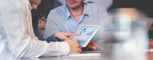 Financial advisor showing clients projected numbers on a tablet.