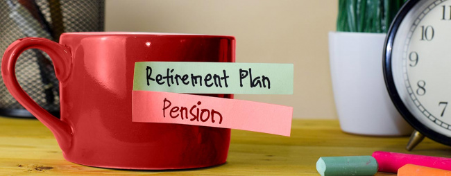 Cup of coffee on top of desk with sticky notes reading, retirement plan and pension.