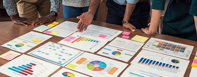 Closeup business man and businesswoman hands understanding pie and bar graphs during meeting.